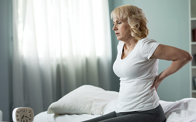Image of a woman on the bed with back pain